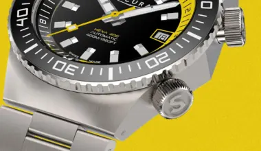 Close-up of a stainless steel dive watch with black and yellow dial, rotating bezel, and date window on a yellow background.