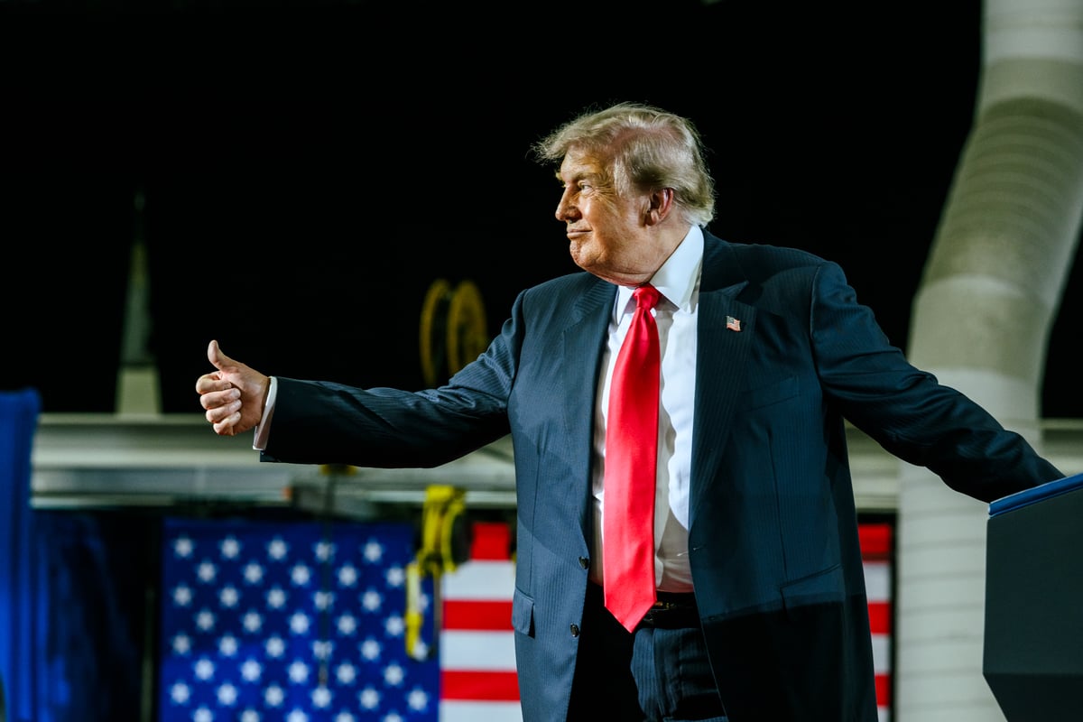 Donald Trump giving a thumbs-up to a crowd during a speech.