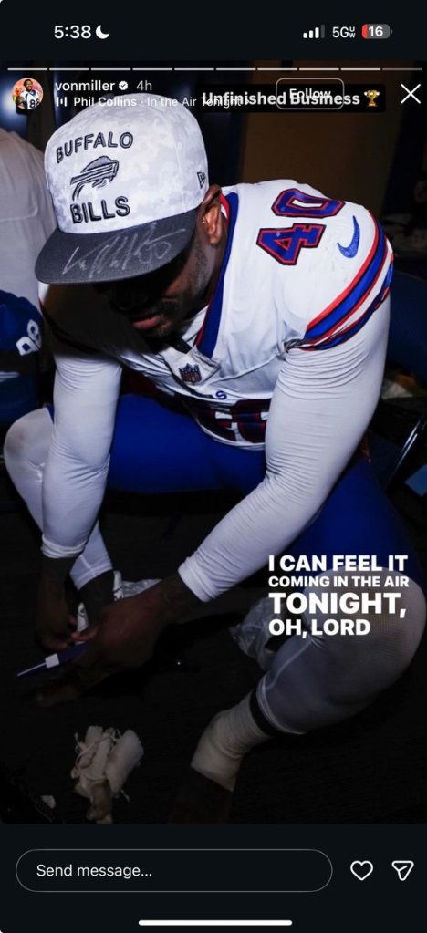 Von Miller tying his shoes while wearing a Buffalo Bills cap and jersey.