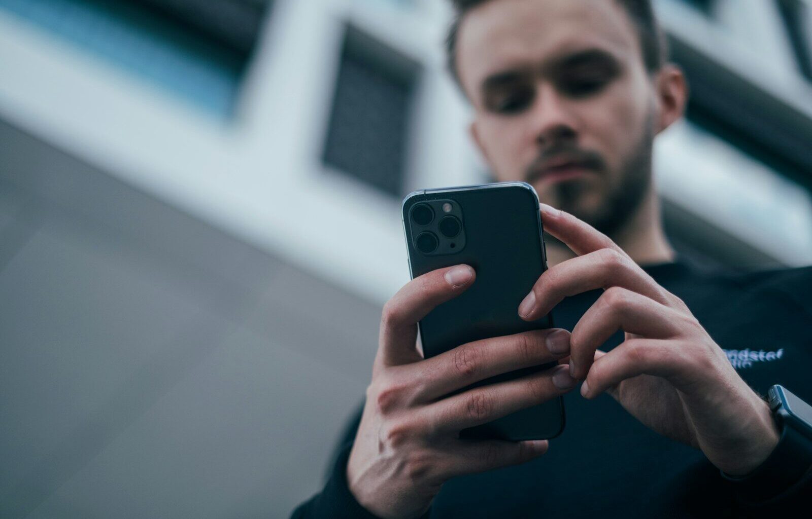 man wearing black sweater using smartphone