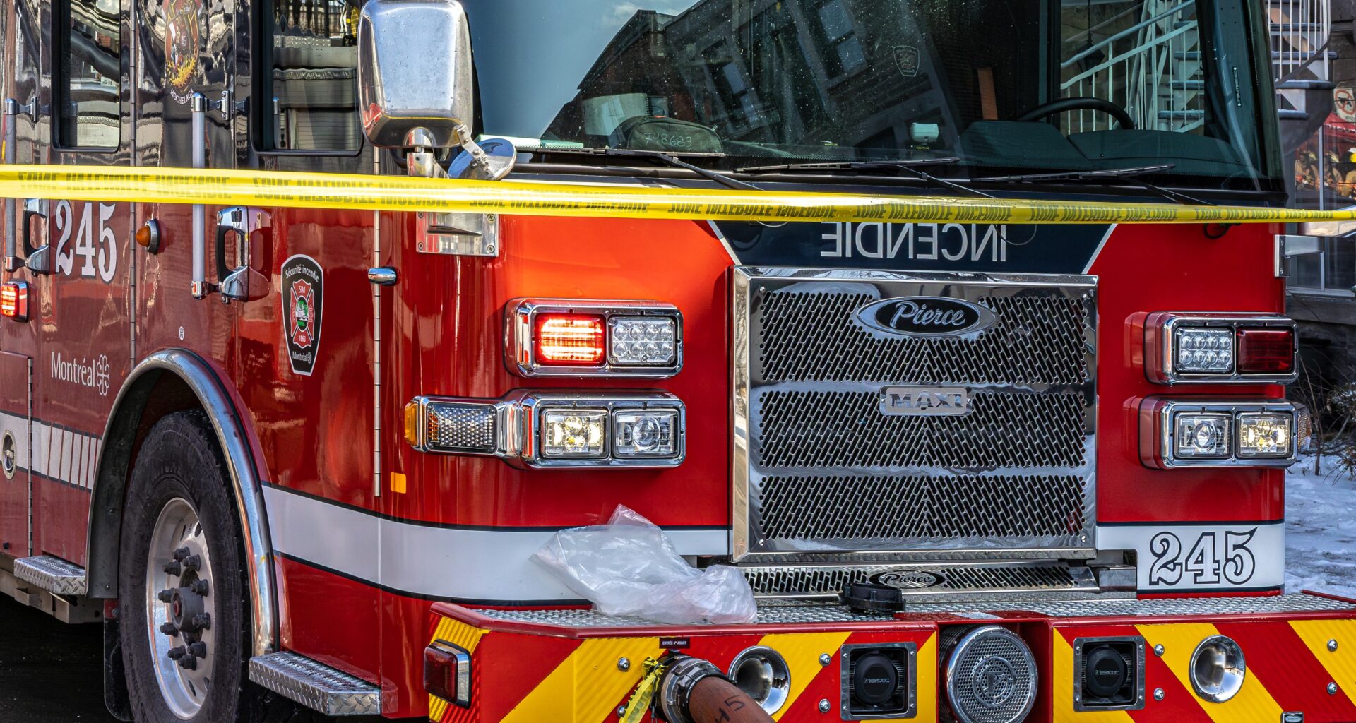 The front of a fire truck, with police tape across the front of it.