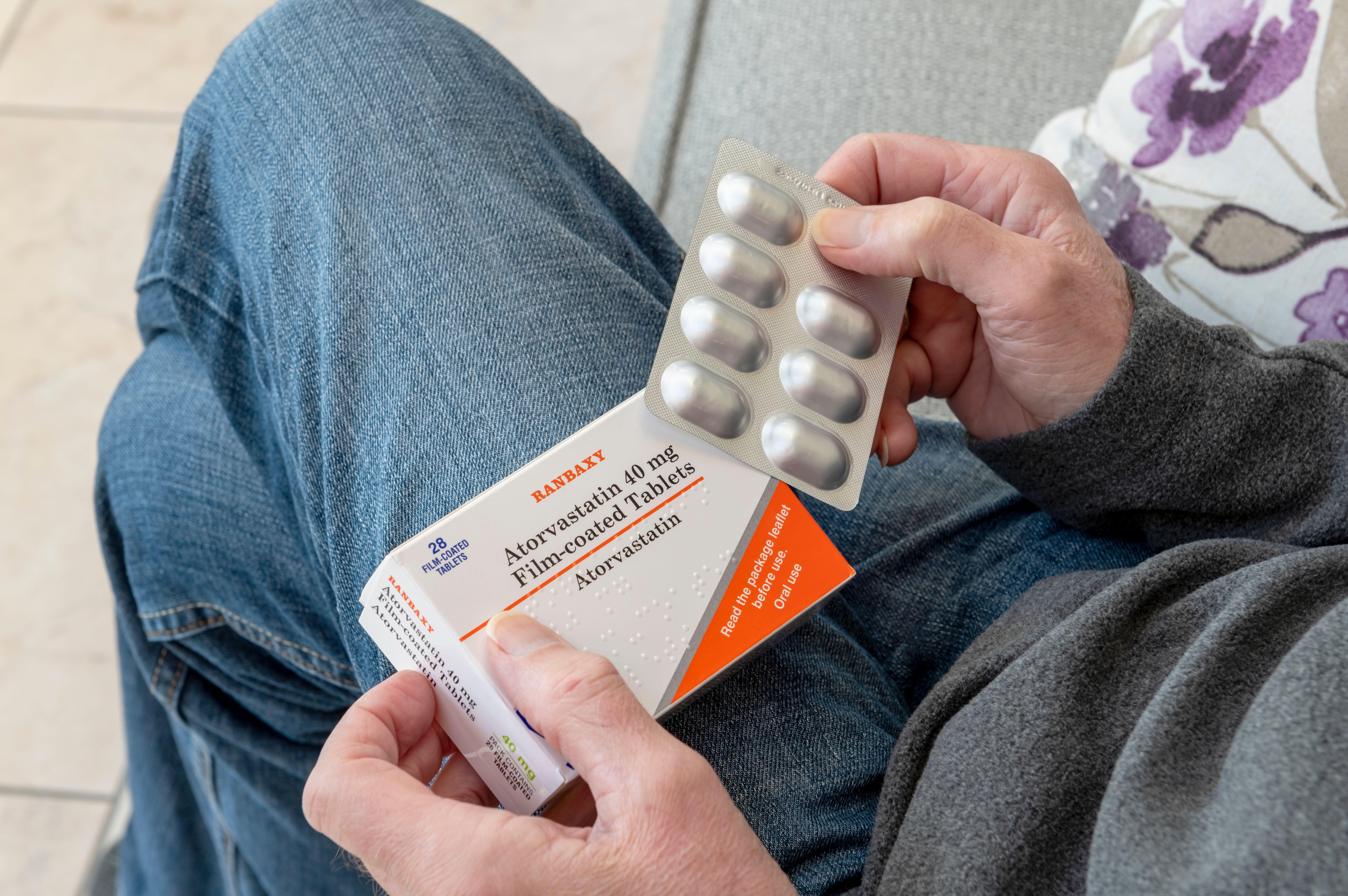 Man holding blister pack box packet of Atorvastatin statins.