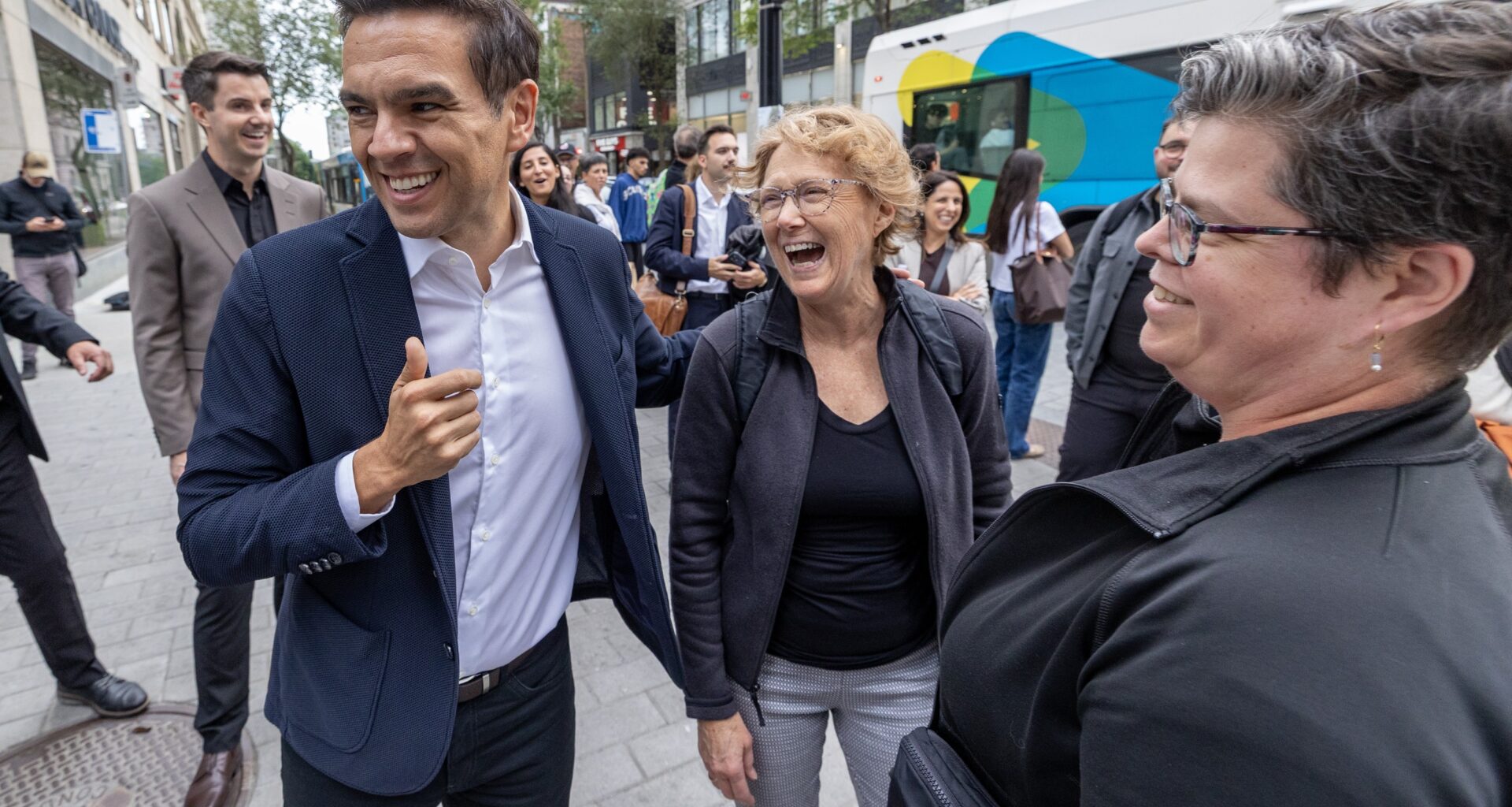 Charles Milliard laughs with two women and others on the street.