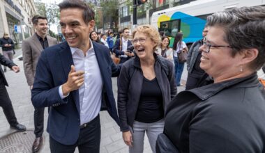 Charles Milliard laughs with two women and others on the street.