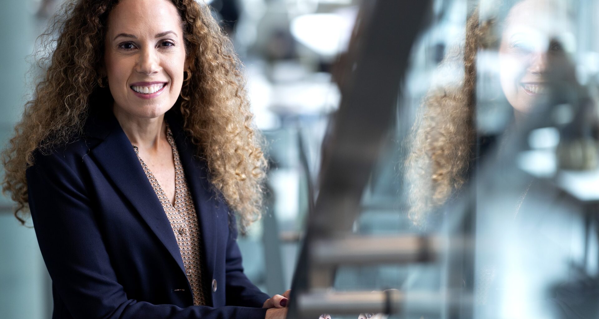 A woman poses in an out-of-focus office environment