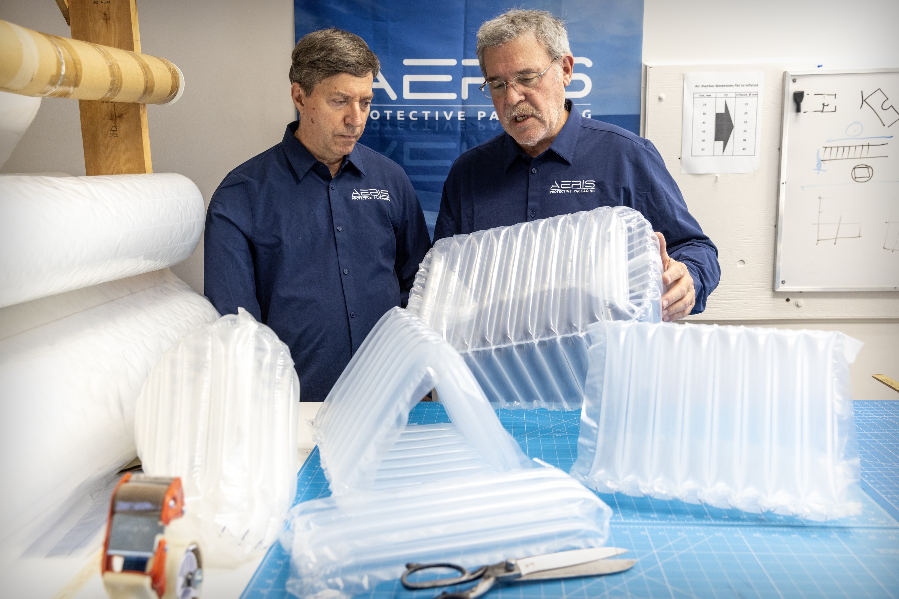 Two men talk as they look at protective packaging for shipping products