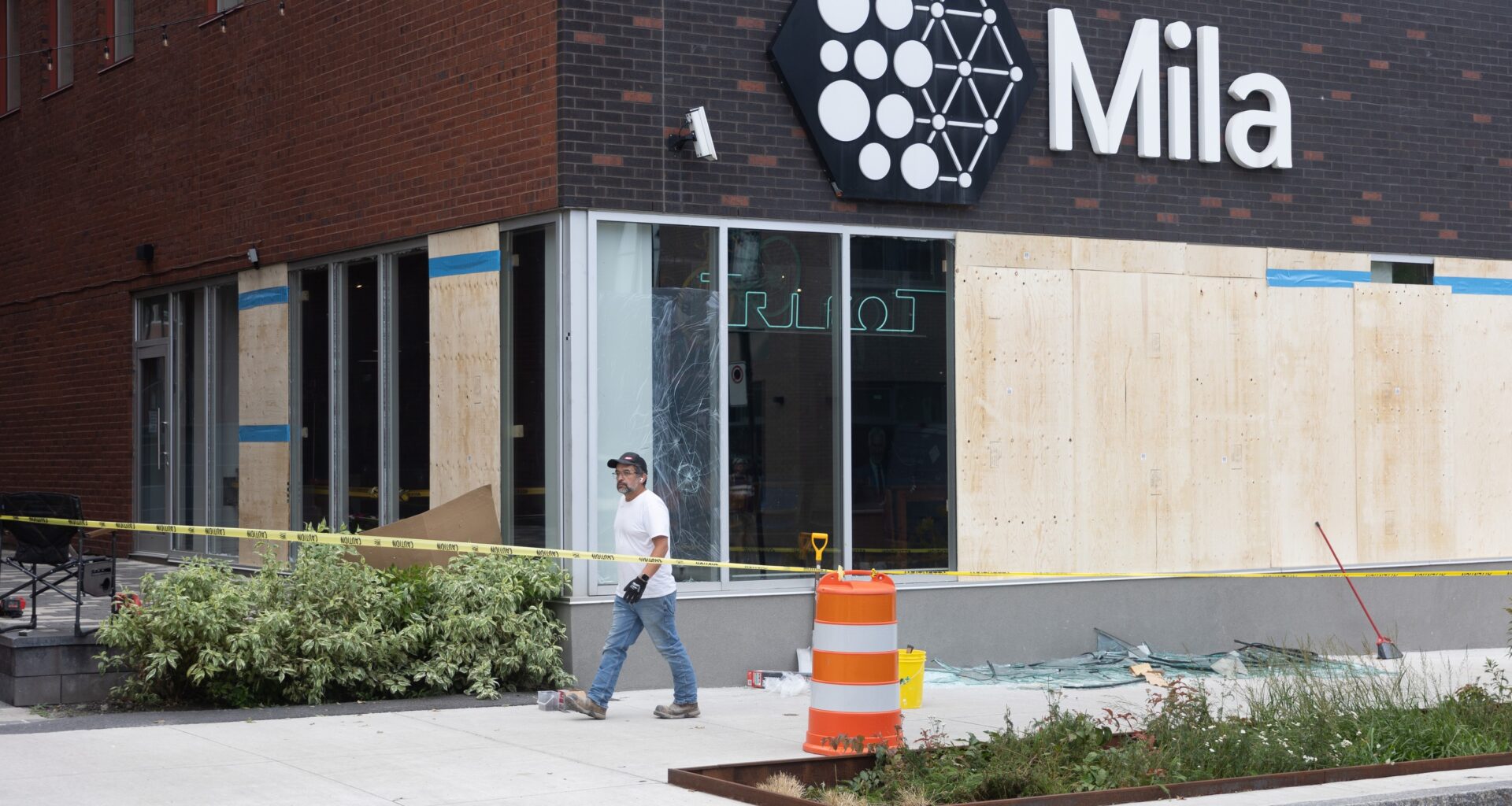 A building with a "Mila" sign and multiple boarded up windows