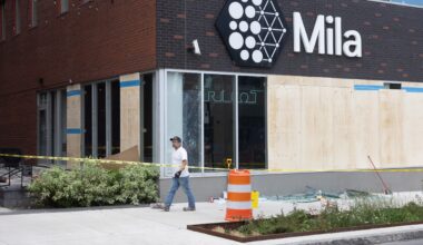 A building with a "Mila" sign and multiple boarded up windows