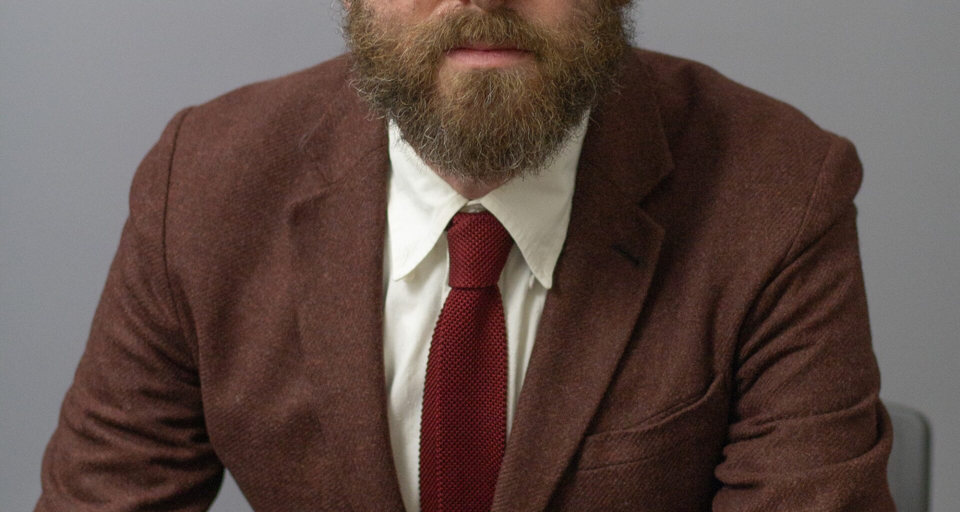 Seated man wearing glasses and brown suit