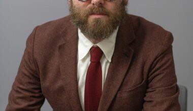 Seated man wearing glasses and brown suit