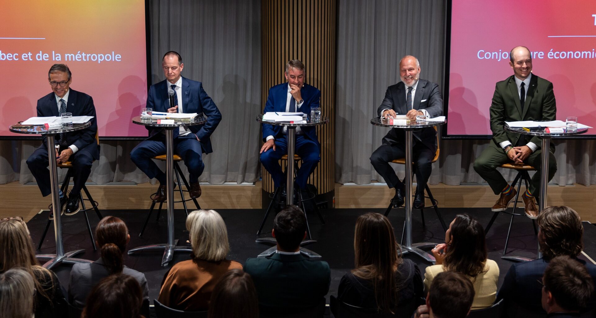 Politicians sit at podiums during a debate.