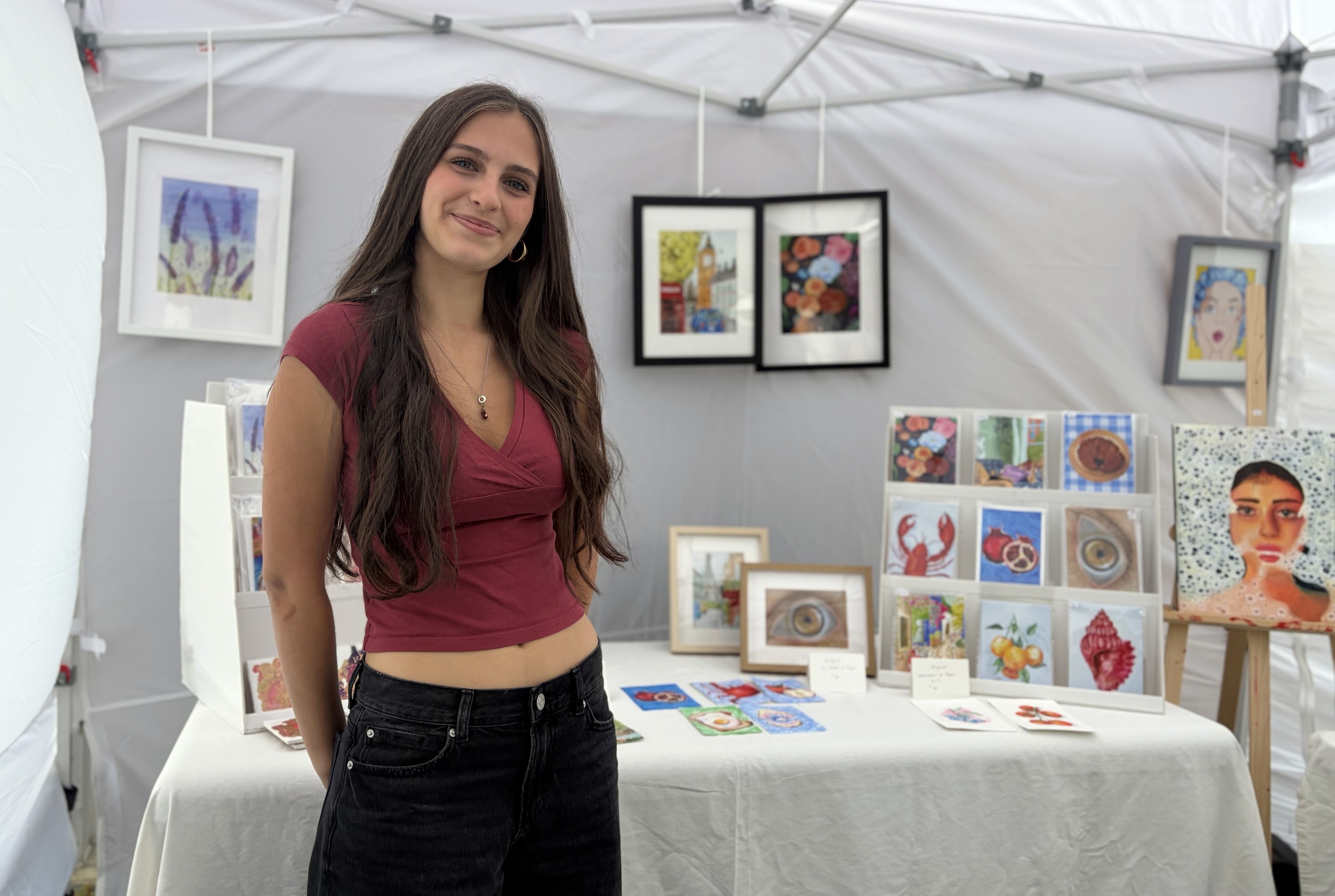 Teenager standing with her artwork mounted on display behind her