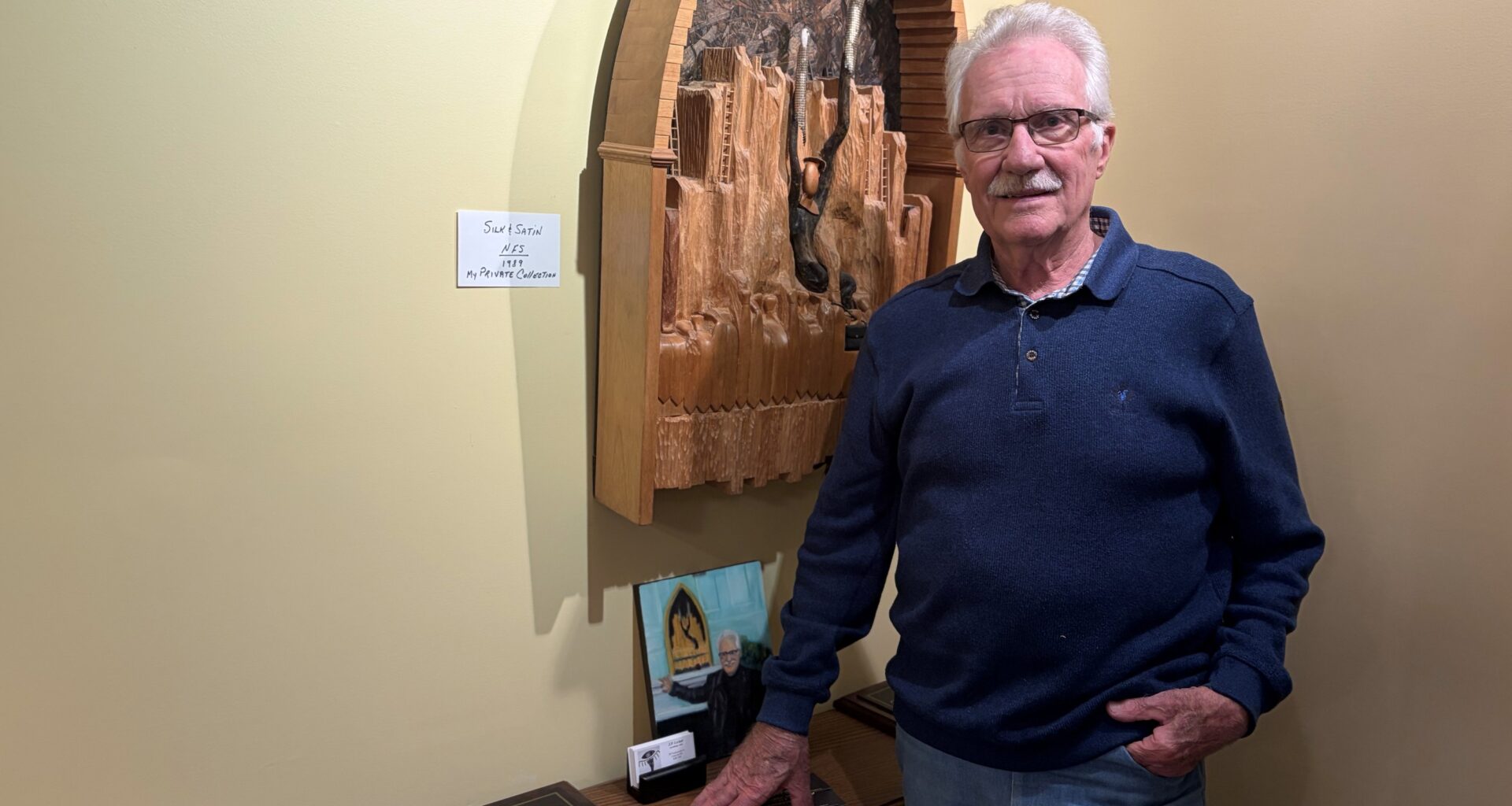 Man standing in his home studio with one of his sculptures in the background