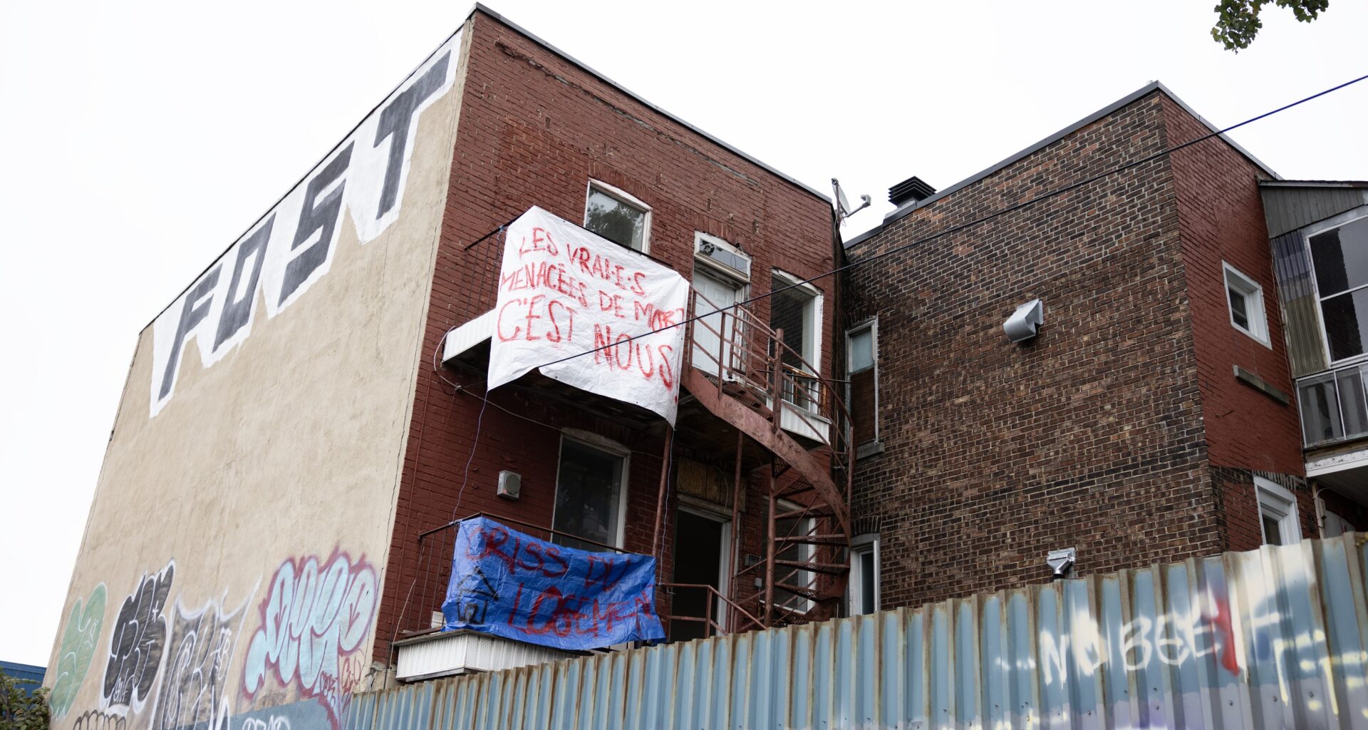 Brick building on corner of street with protest sign up high on it.