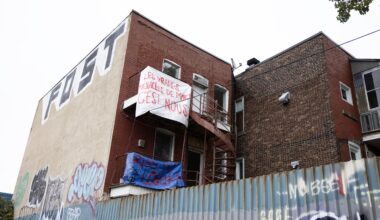 Brick building on corner of street with protest sign up high on it.