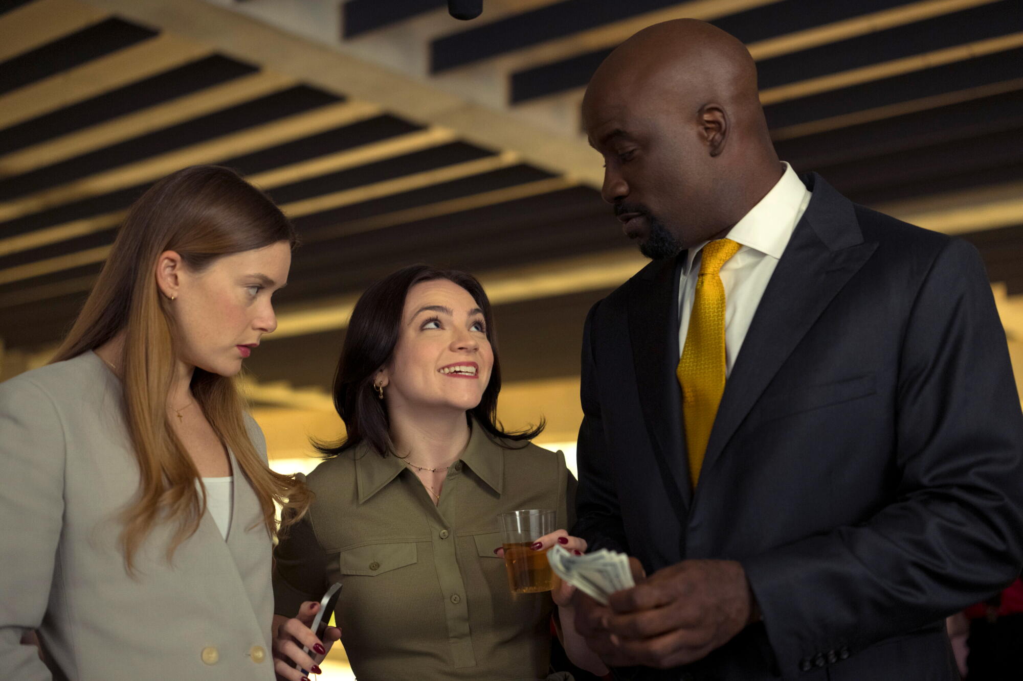 A pair of women stand next to a man in a dark suit and tie.