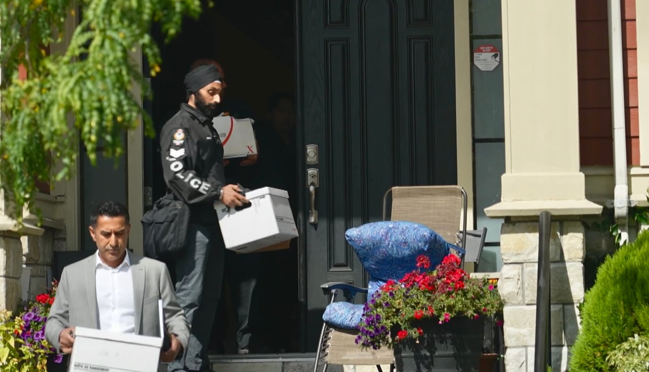 Two police officers removing items from the home of VPD officer Kalwinder Dosanjh