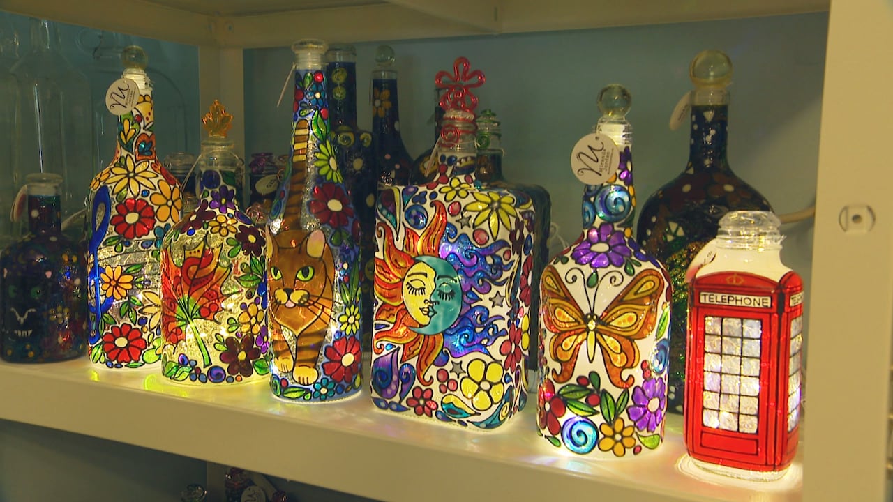 A row of colourful hand-painted glass bottles which have been turned into lamps.