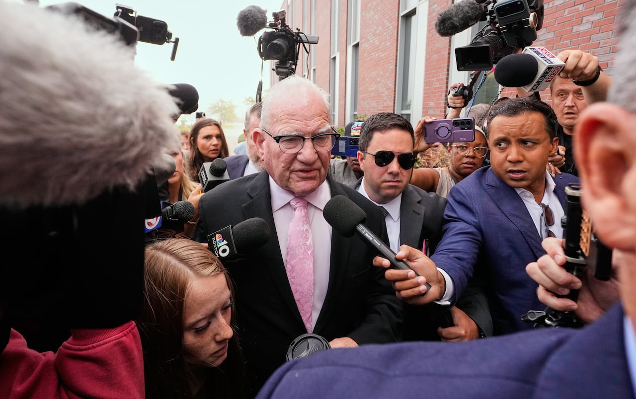 A man walks through a crowd of people holding microphones
