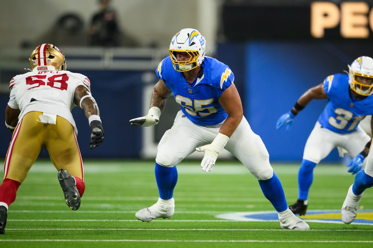 A football player prepares to block an opposing player rushing toward the quarterback.