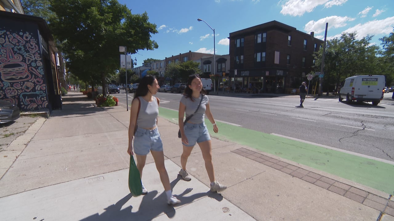 Two women walking on a sidewalk in Toronto.