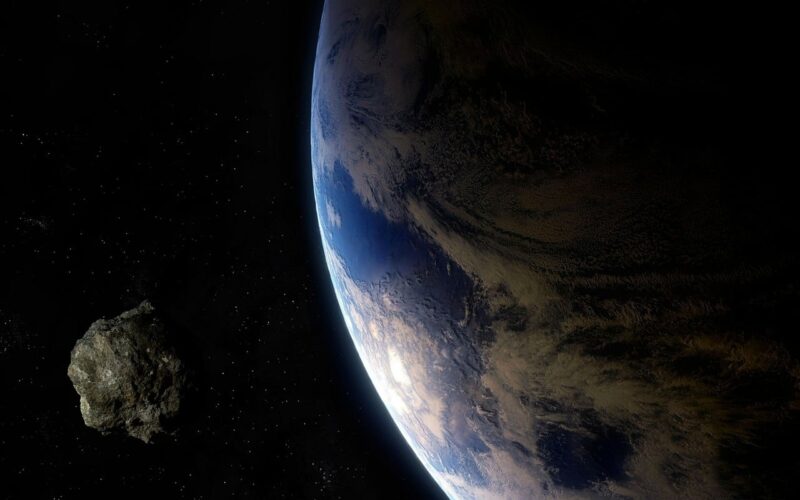 Earth as seen from space on the right with a small rocky body on the left.