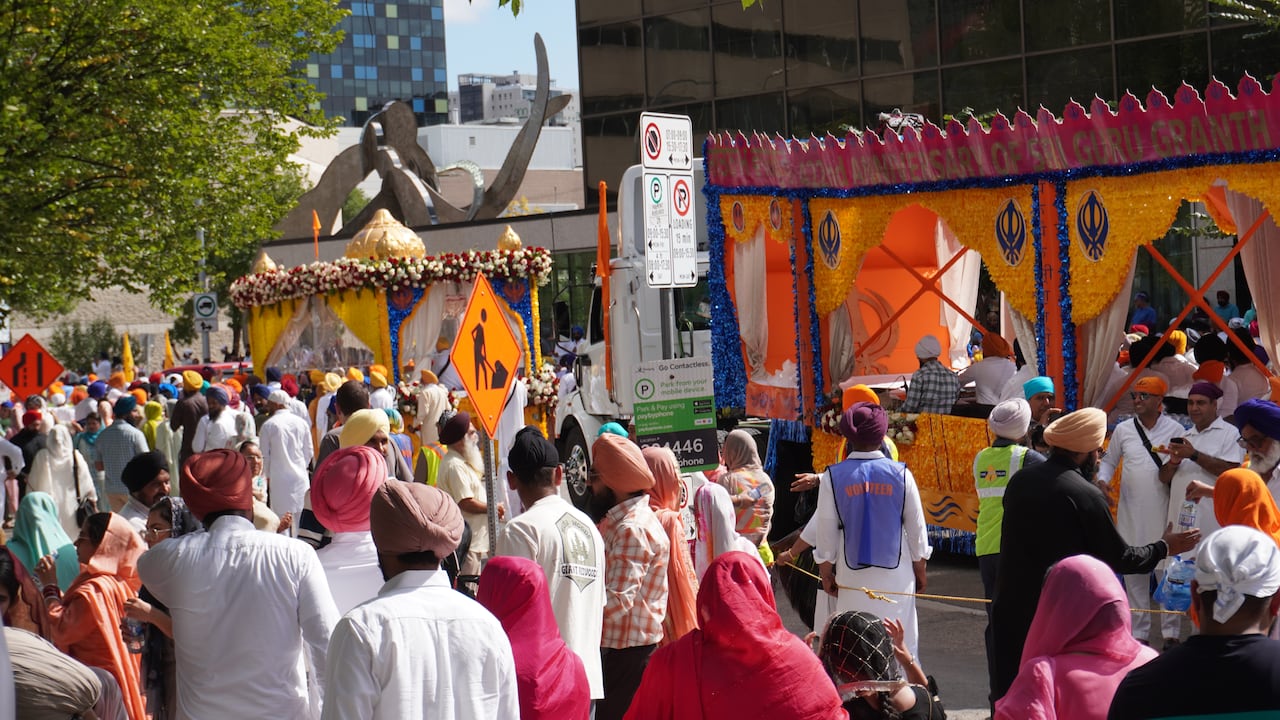 Lots of people alongside displays of Sikh culture on a road in downtown Winnipeg.