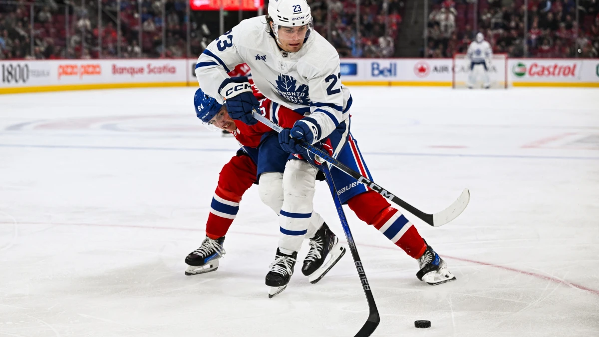 Toronto Maple Leafs left wing Matthew Knies (23) plays the puck against Montreal Canadiens defenseman David Reinbacher (64) during the third period at Bell Centre.
