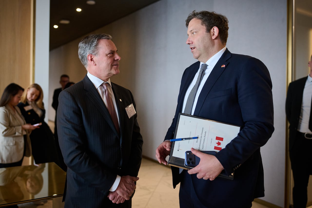 Two men in suits are talking at a business meeting.