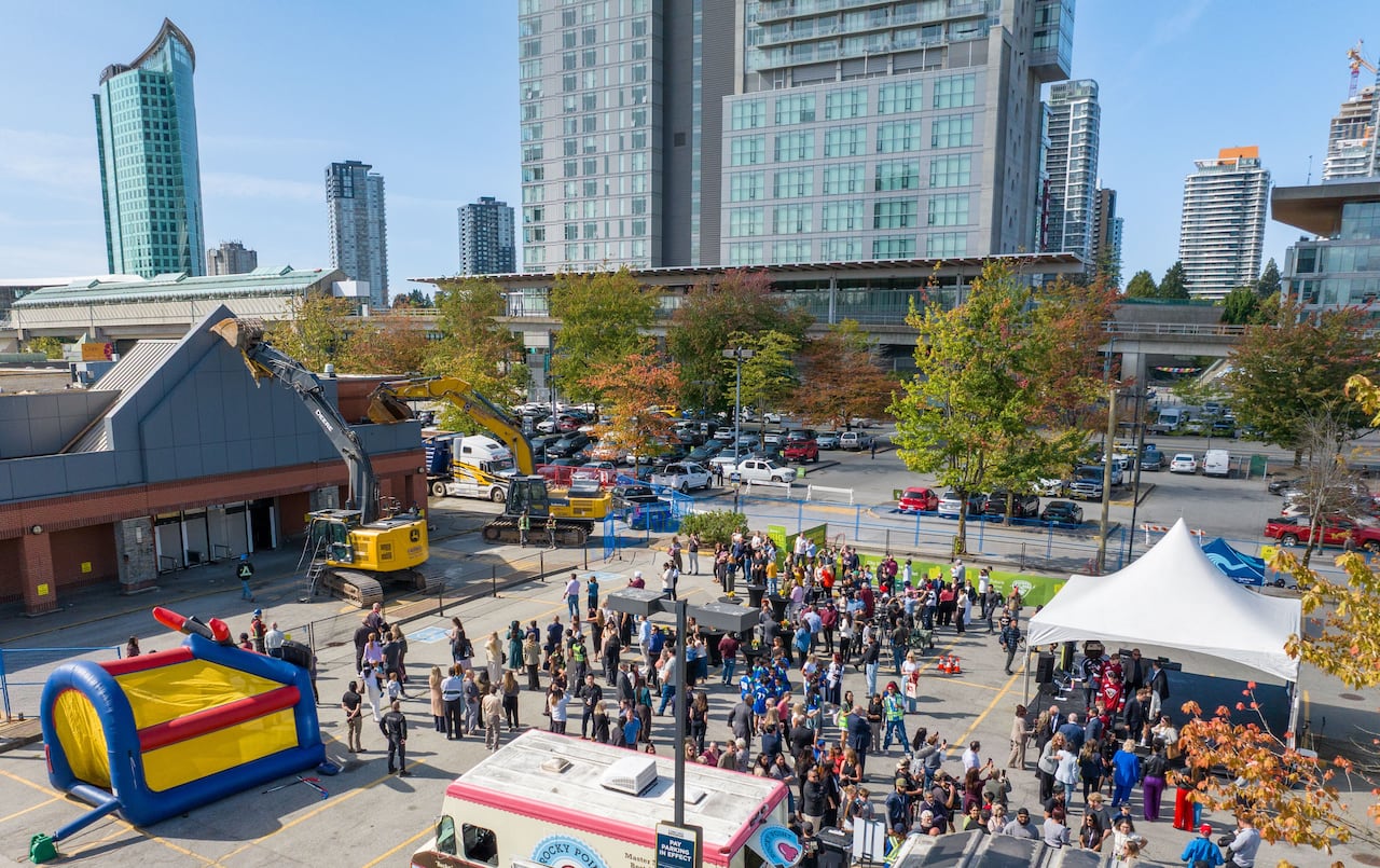 A crowd of people are pictured in a parking lot in front of a building to be demolished, in Surrey, B.C.