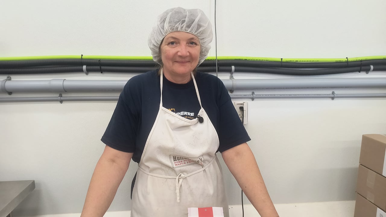 a woman smiling with a bag of maple sugar underneath