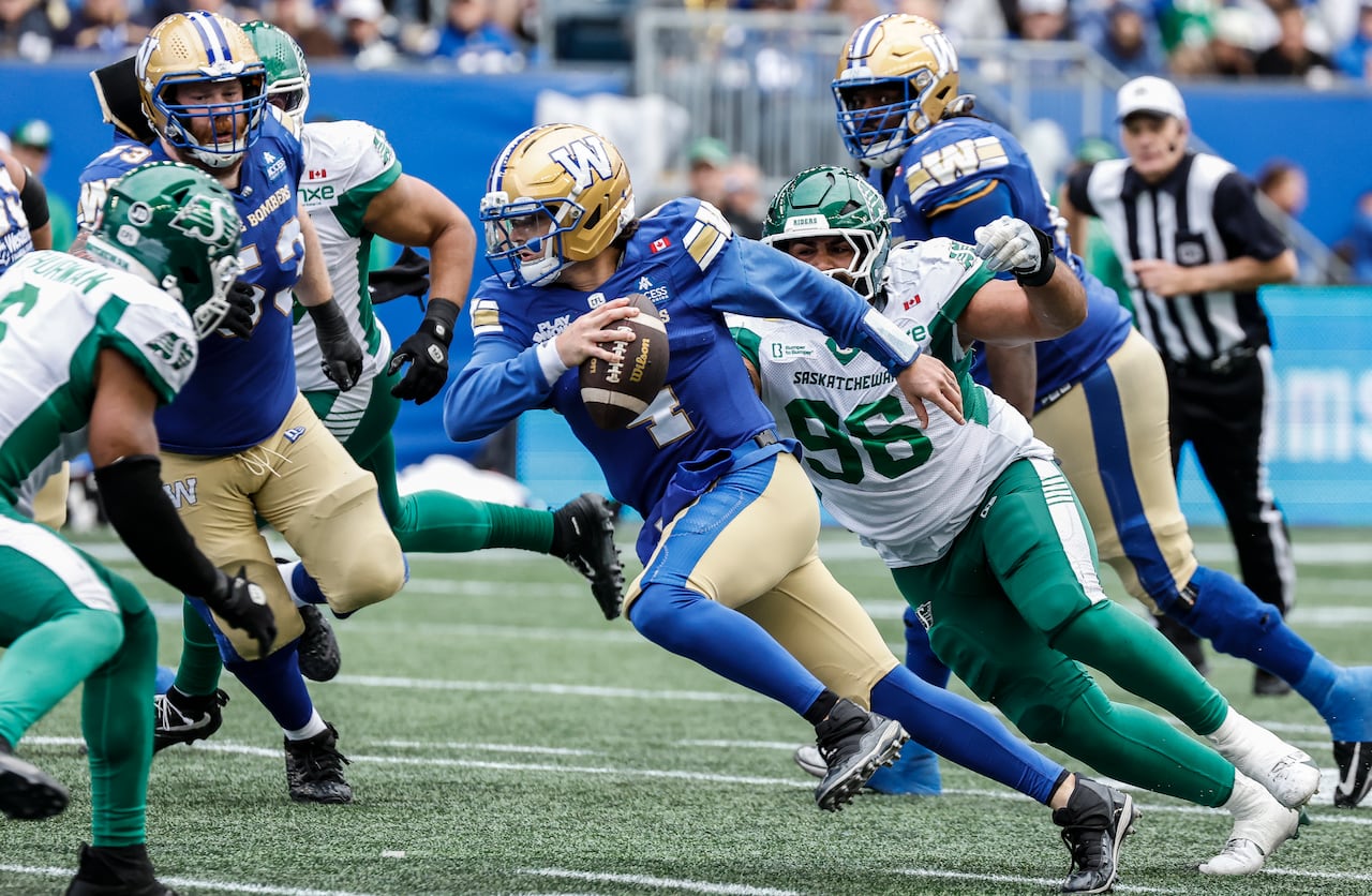 A football player in a blue and gold uniform runs with a football while surrounded the other players in the same uniform and players wearing green and white uniforms