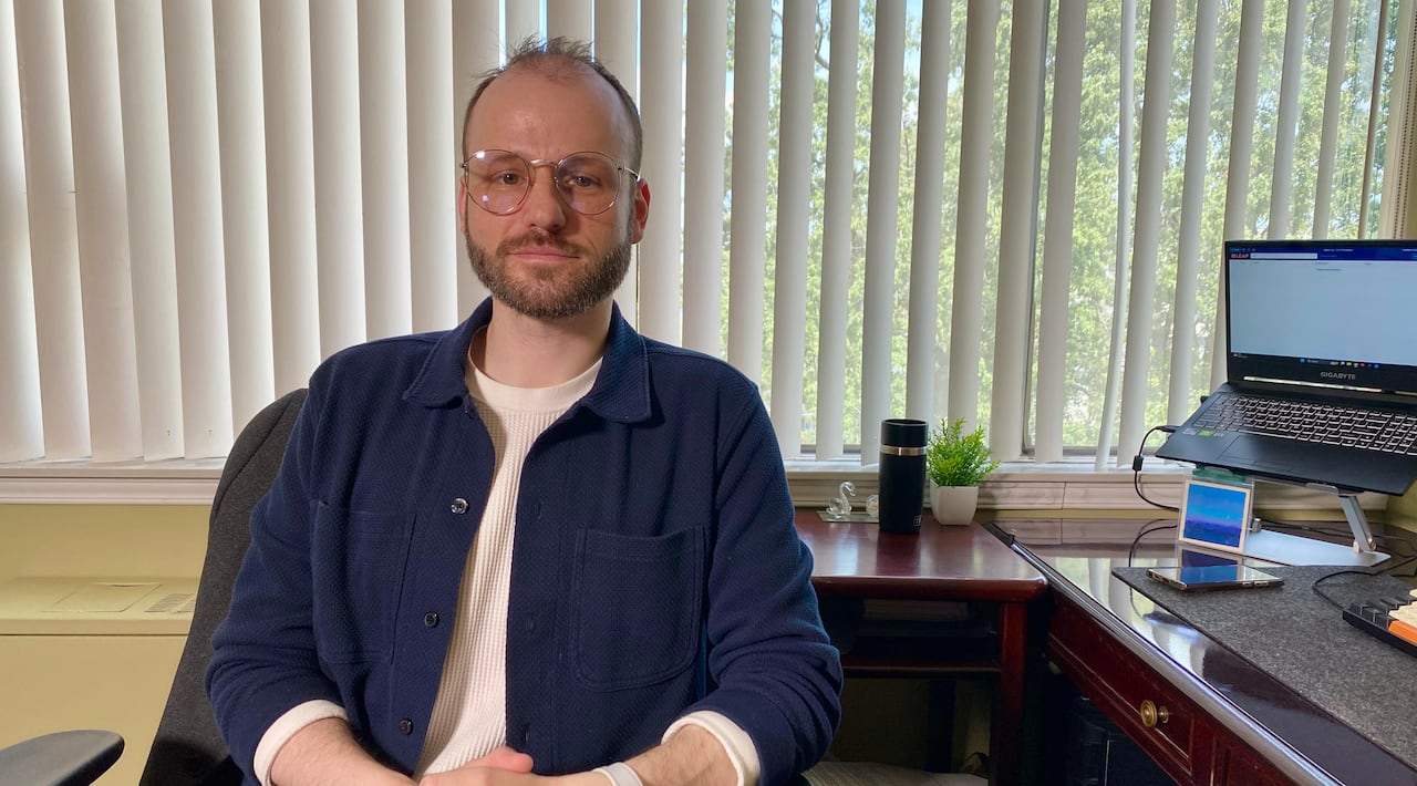 Andrew Ballantyne sits at his desk.