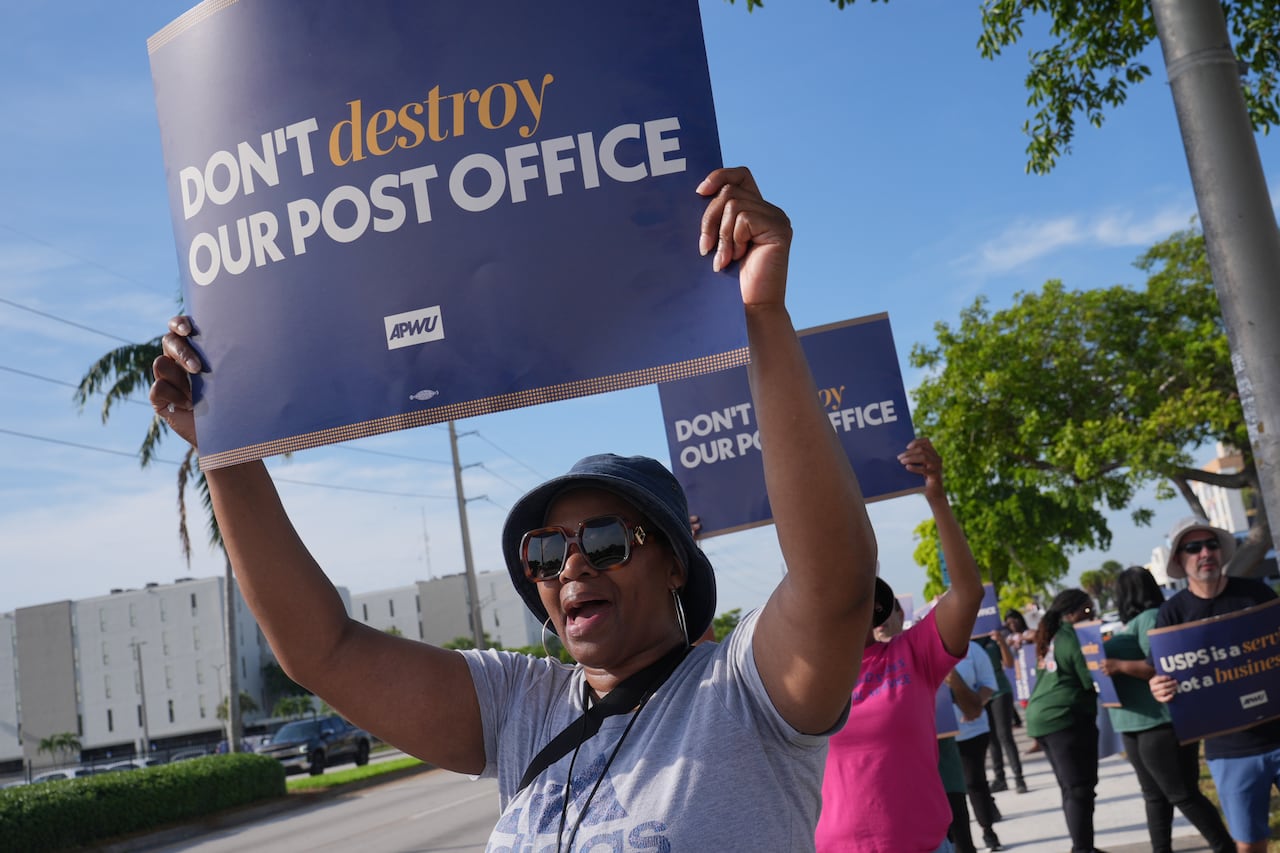 Person holds a sign up that says Don't Destroy our Post Office