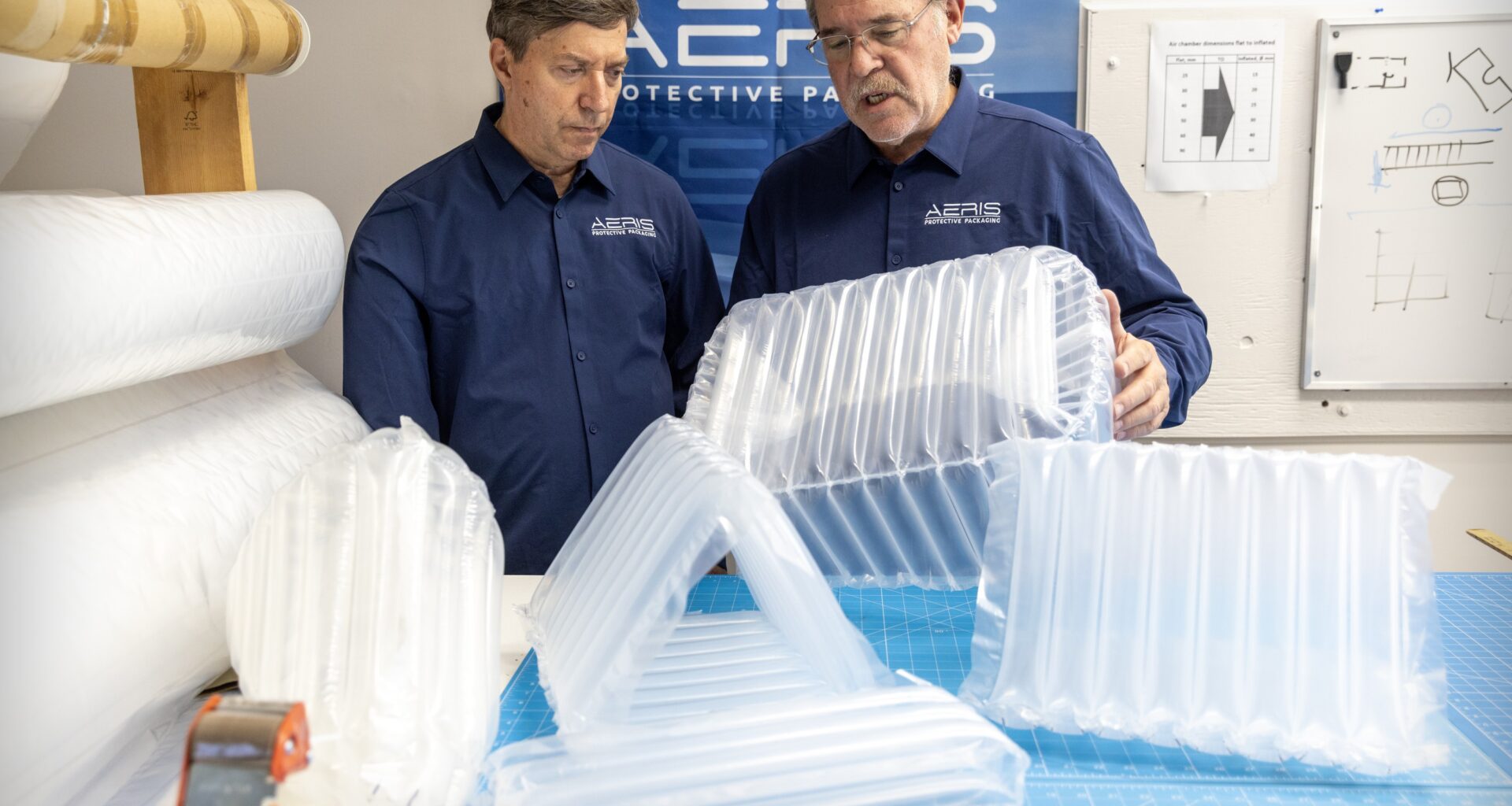 Two men talk as they look at protective packaging for shipping products