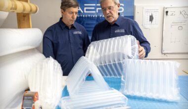 Two men talk as they look at protective packaging for shipping products