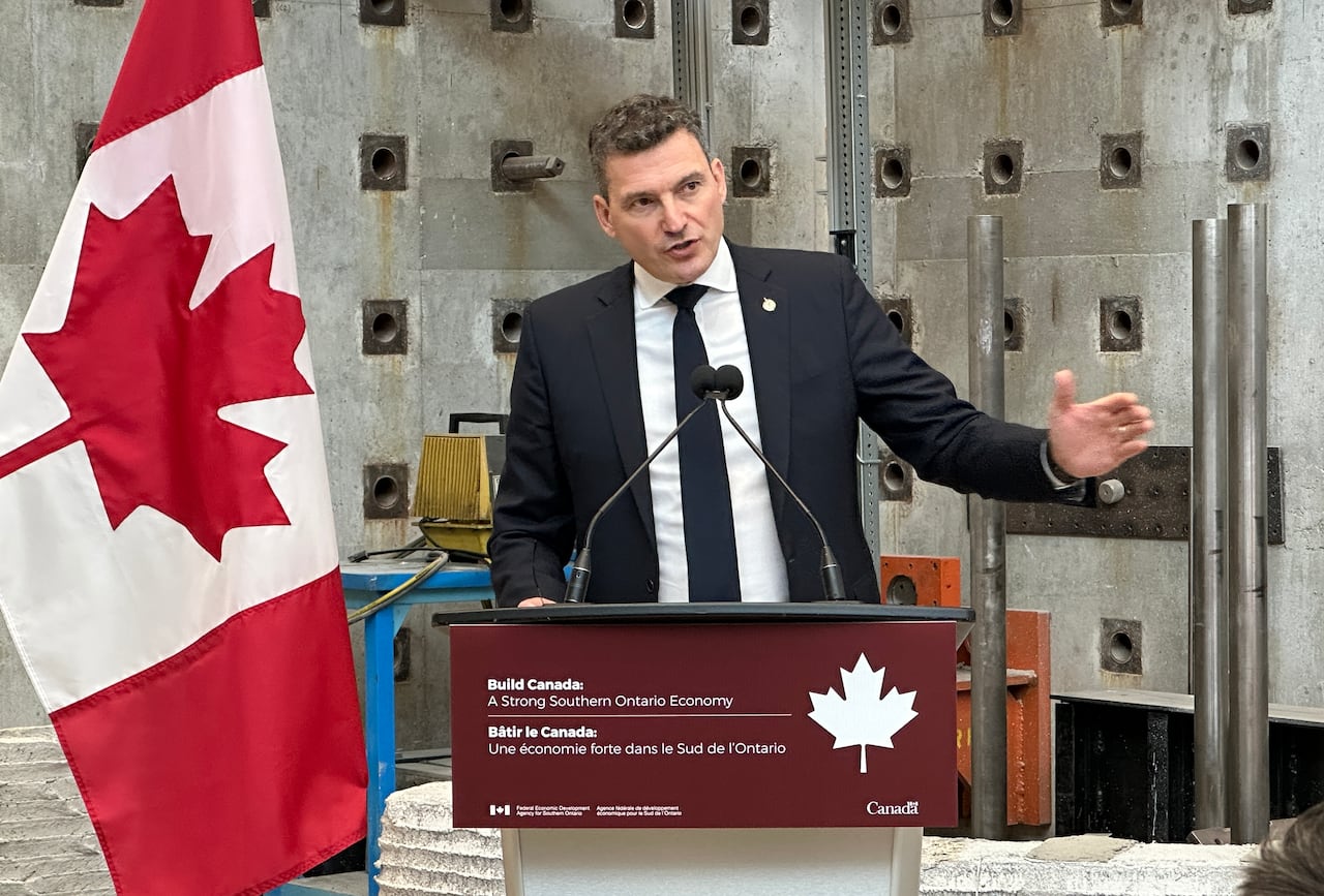 A man in a business suit speaks at a podium.