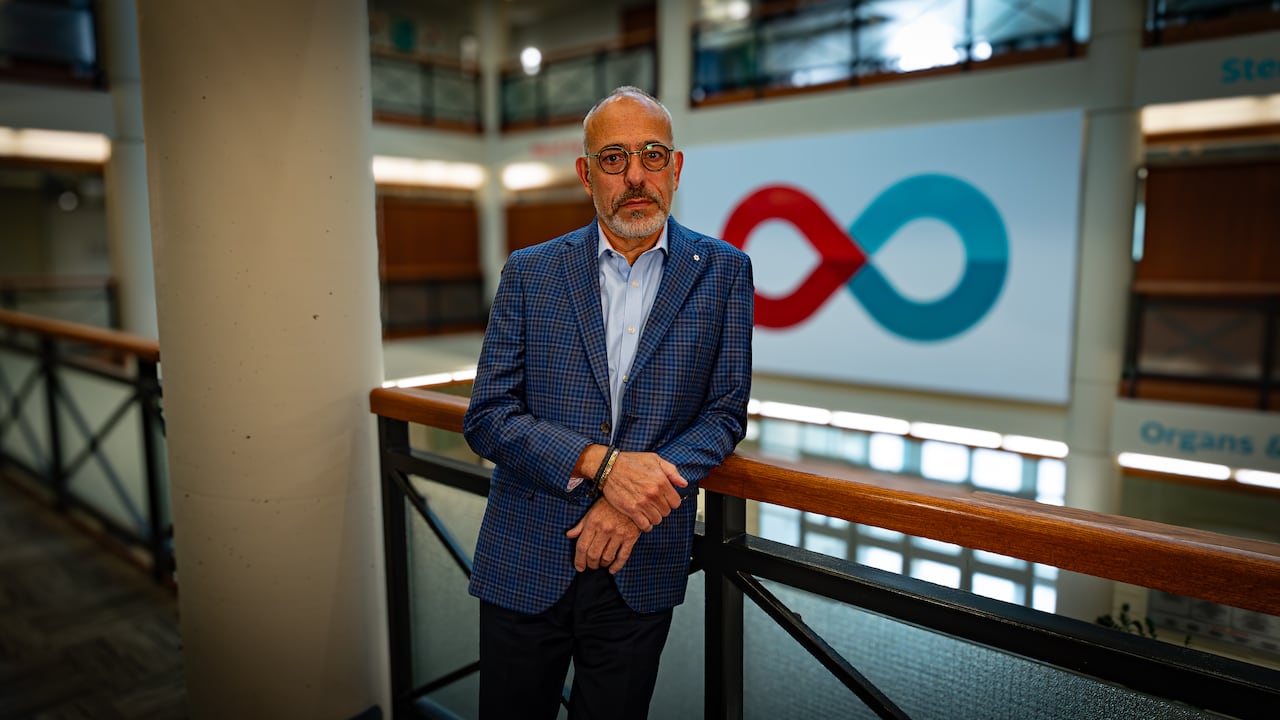 A picture of a man with little hair and glasses leaning on a rail.