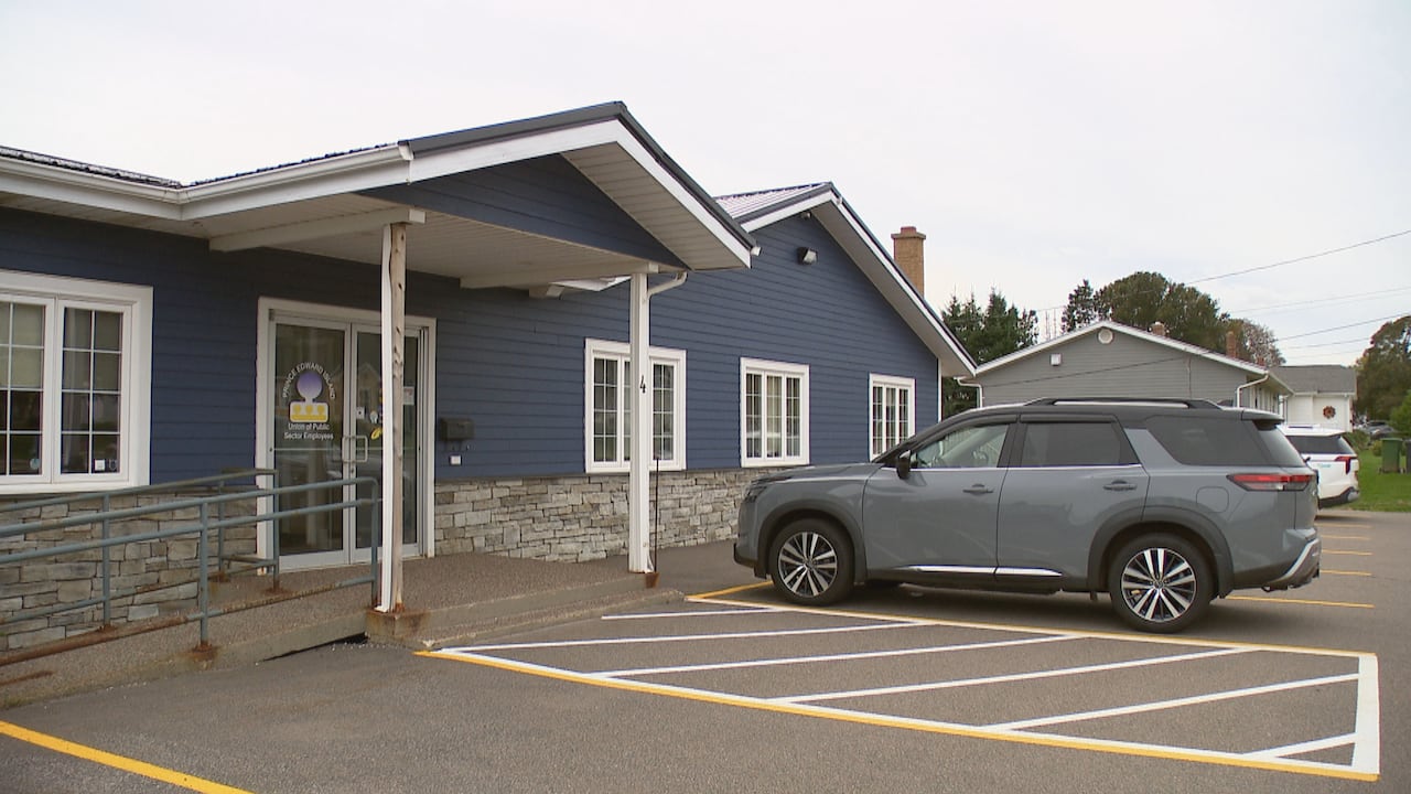 A blue building with an SUV in the parking lot is seen from the outside.