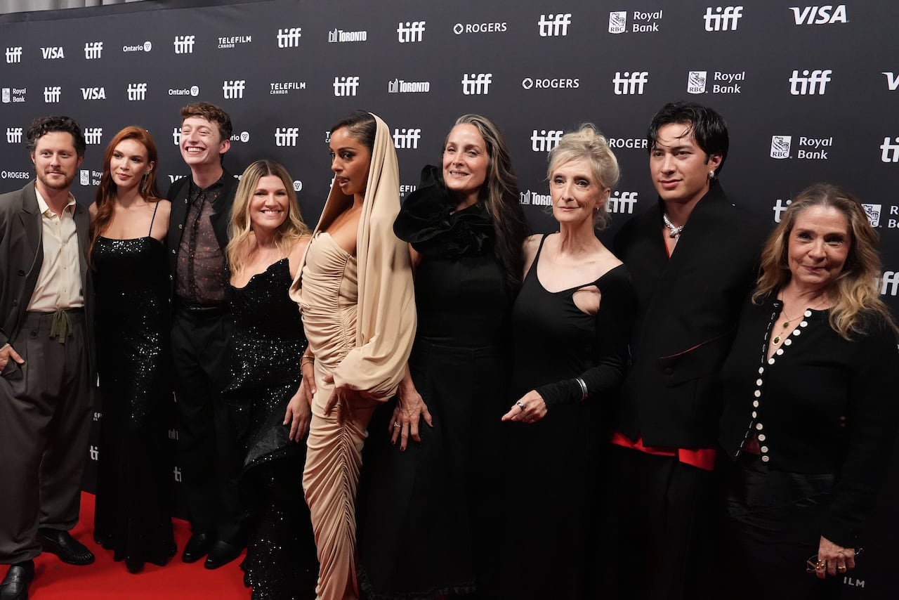 Cast members smile on the red carpet.