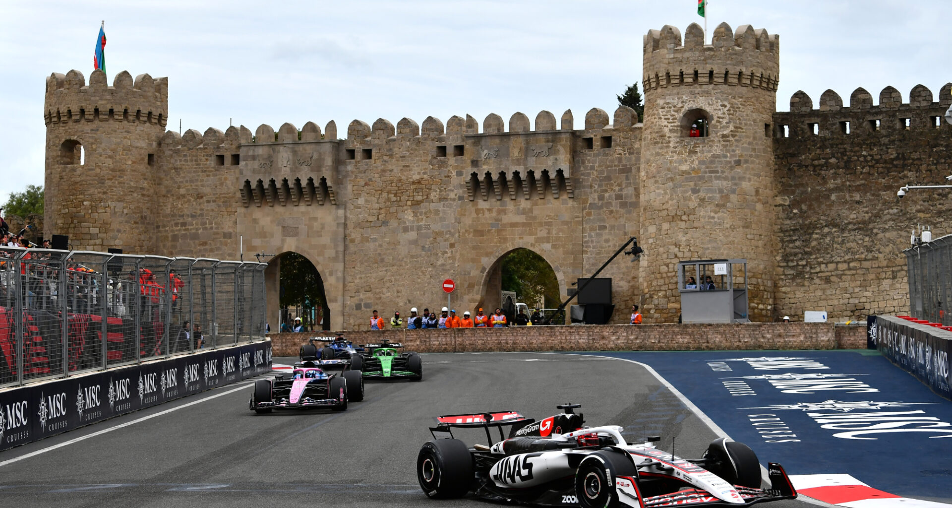 F1 cars driving around the Baku Street Circuit with the Maiden Tower in the background.