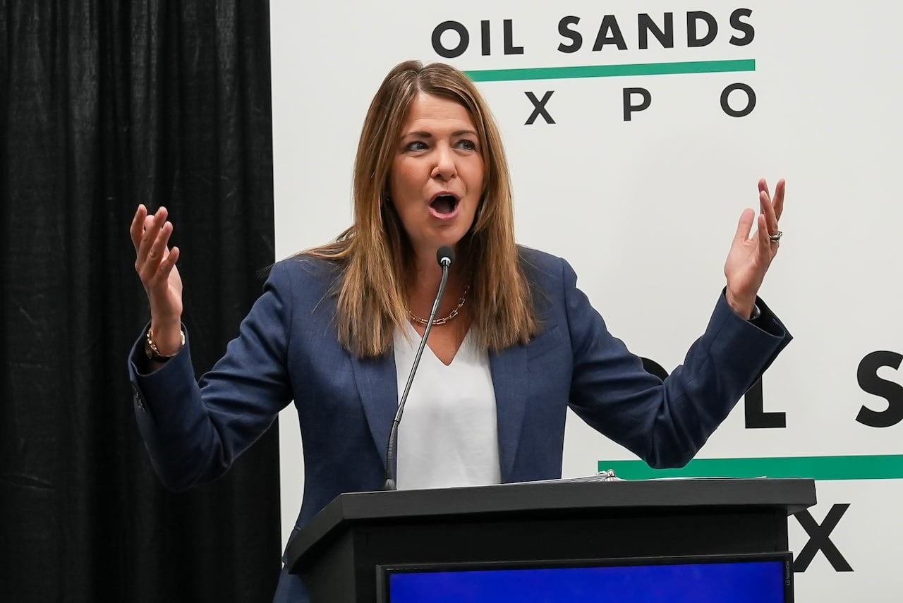 A woman at a podium raises her arms in the air and yells with excitement.