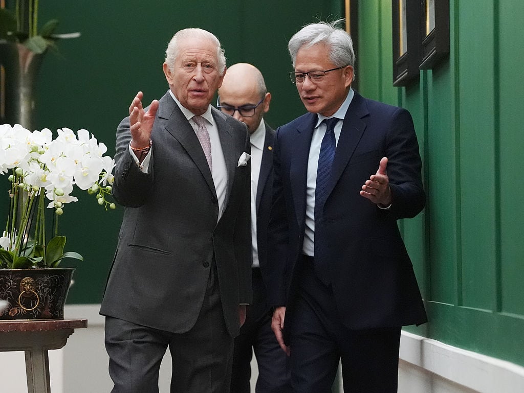 Three people walk beside a green wall.