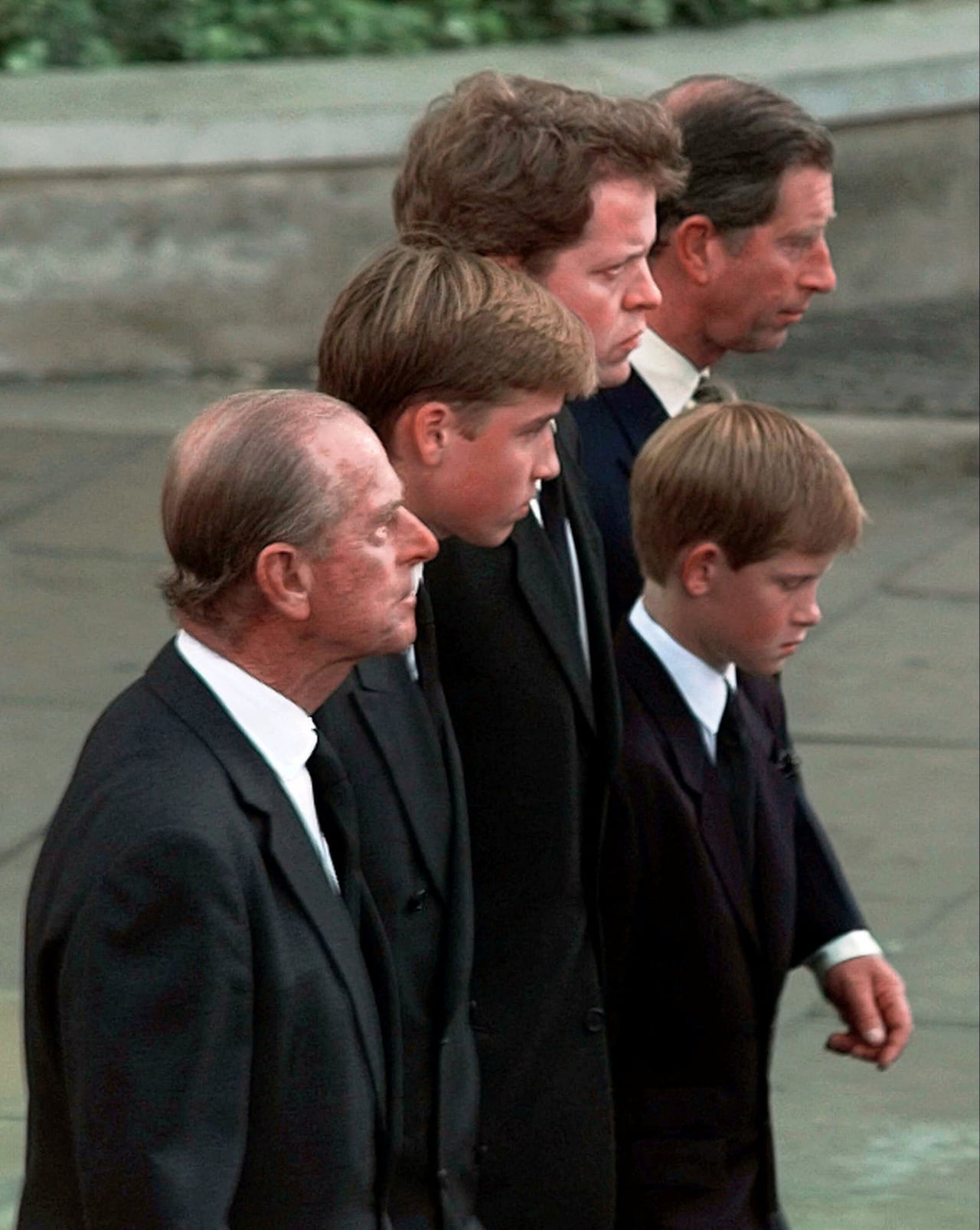 Three adults, a teen and a child walk down a street.