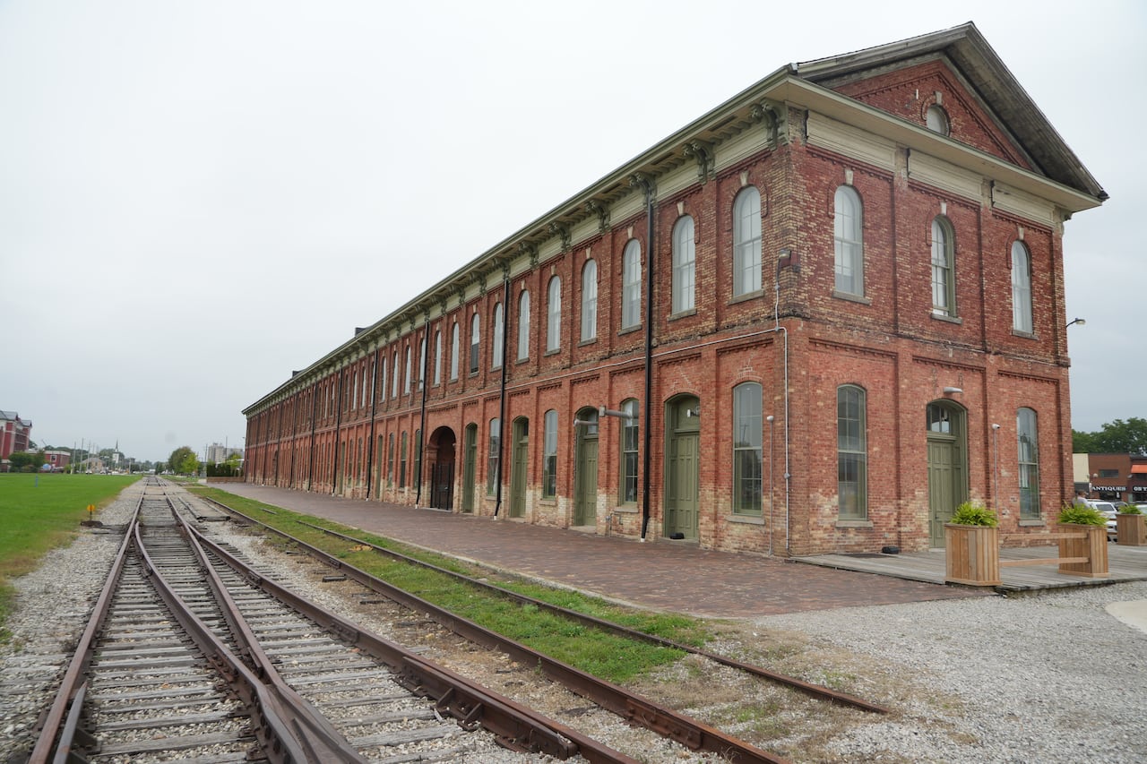 An enormous Victorian railroad station next to rusty tracks.