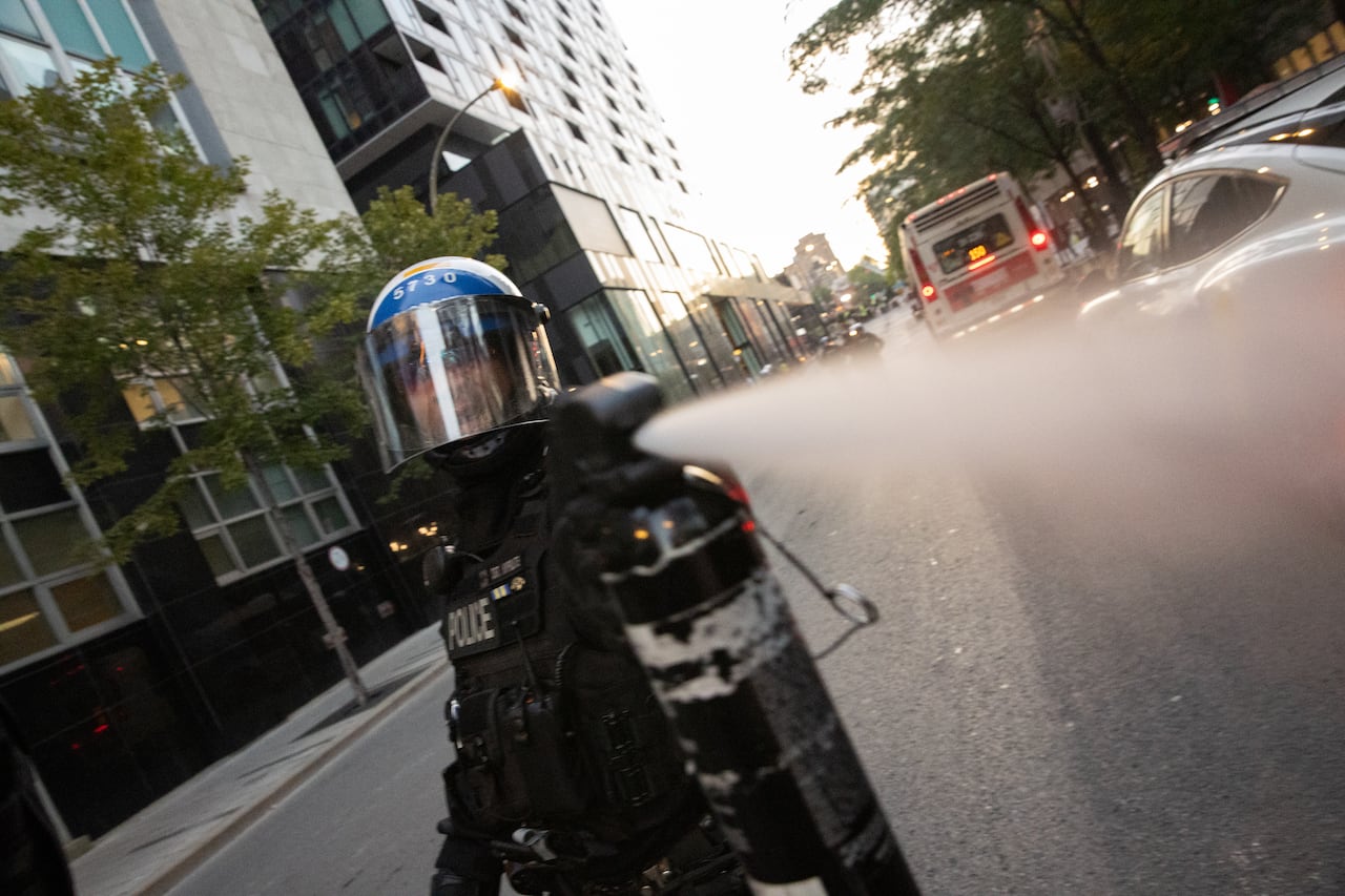 A police officer sprays pepper-spray at the photographer taking the photo.