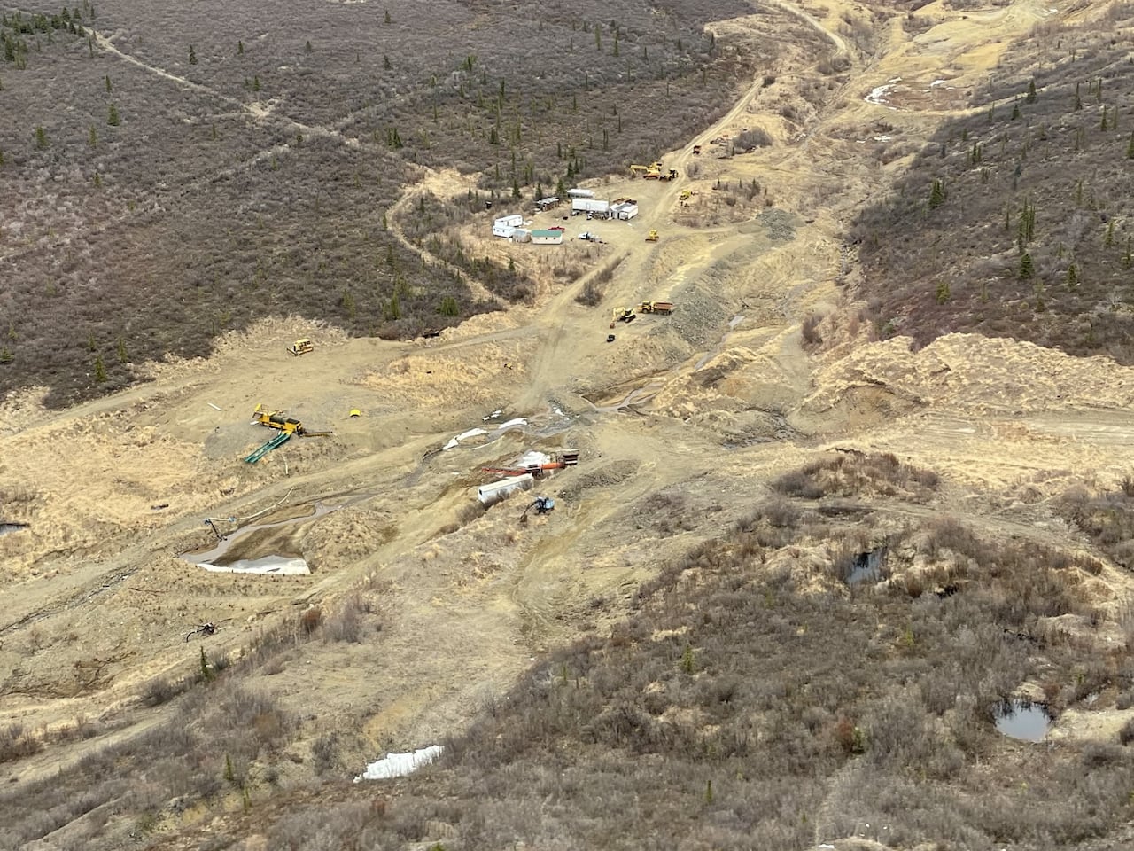 An aerial photo of a placer mine site with scattered buildings and heavy machinery.