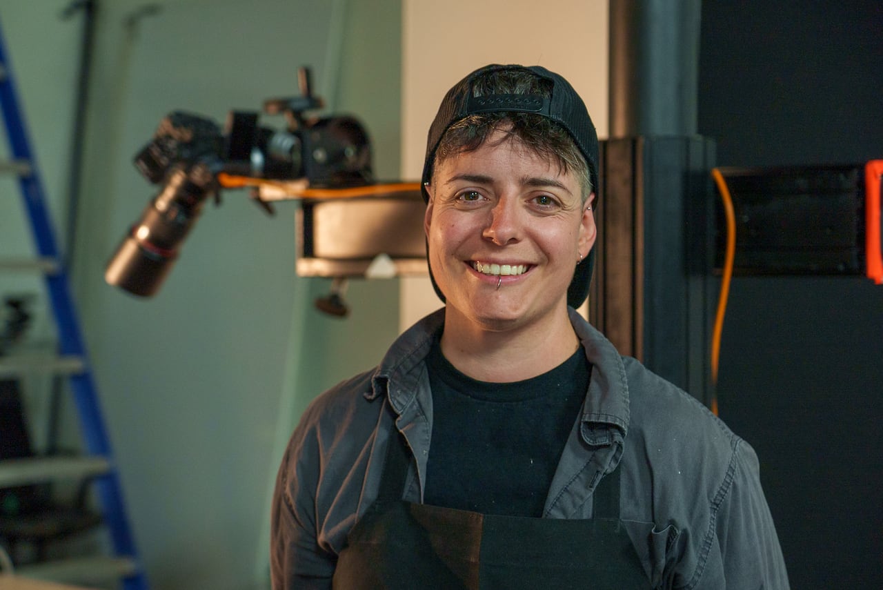 a person with a backwards baseball cap and short hair smiles at the camera in a headshot image