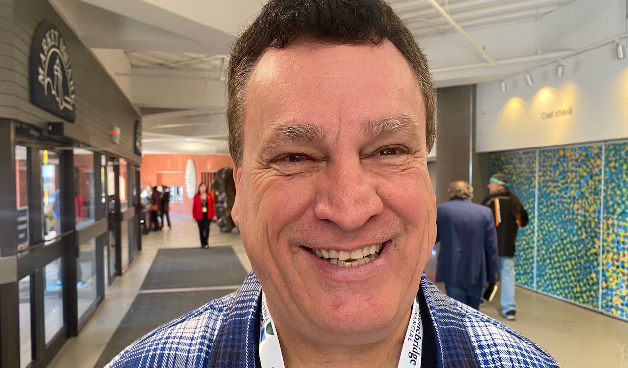 A smiling man with short dark hair stands in the lobby of a convention centre.