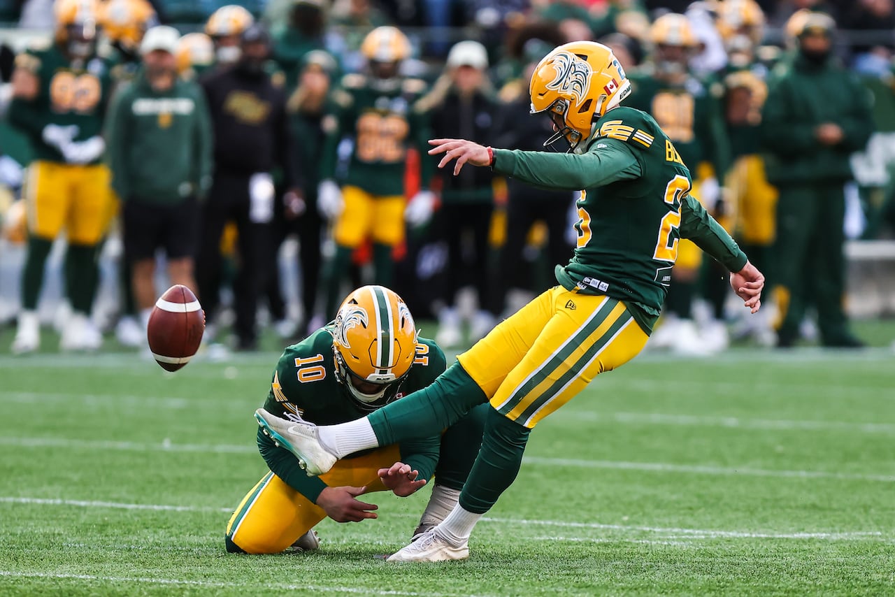 Two men's football players in green-and-yellow uniforms set up to kick a football.
